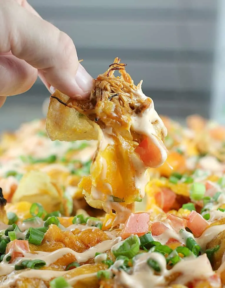 These loaded Sriracha chicken kettle chips are pure game day chaos in the best way. Slow-cooked pulled chicken gets piled onto crispy kettle chips, then topped with bacon, jalapeño, tomato, and loads of melted cheese. Bold, messy, and guaranteed to be a crowd favorite at any watch party.