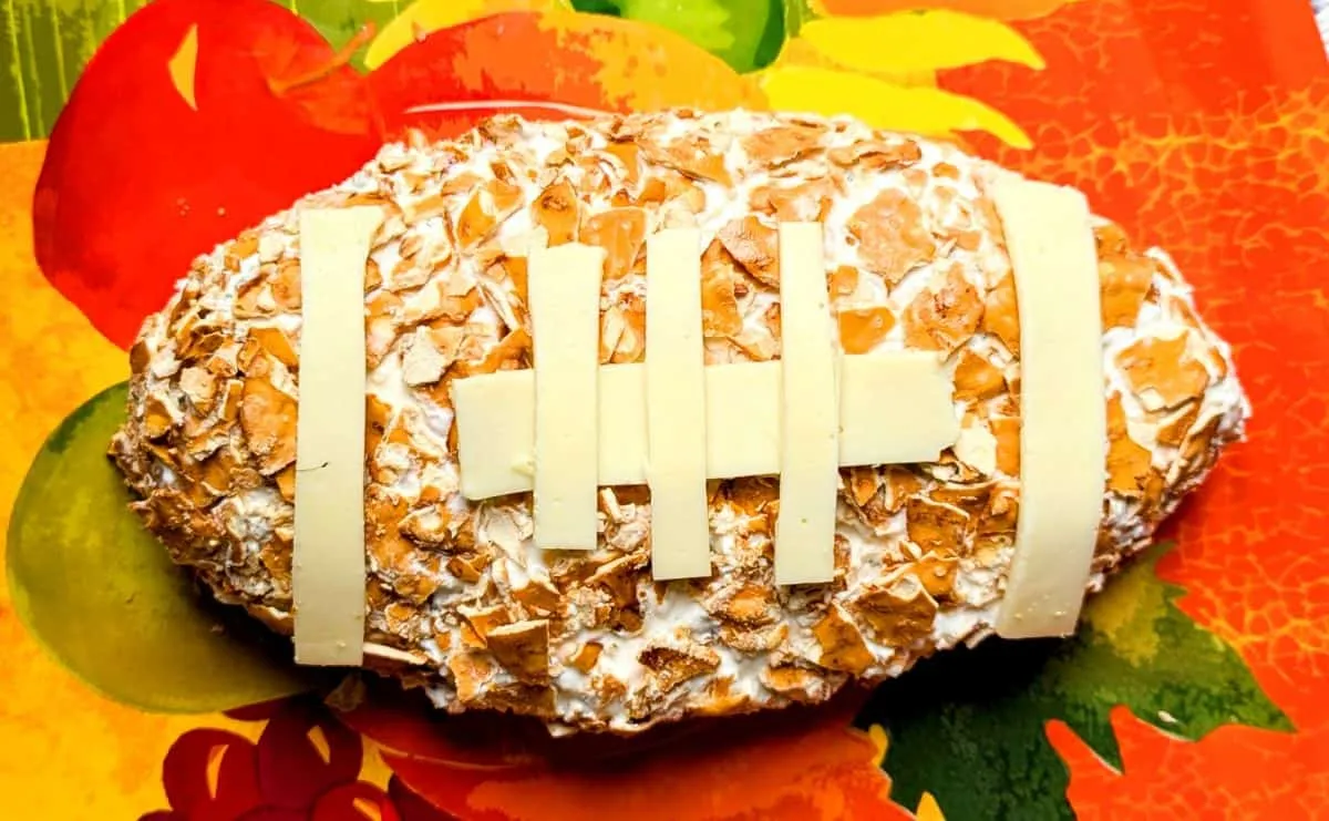 This football cheese ball is an easy win for game day entertaining. Made with cream cheese, sour cream, ranch seasoning, and Colby Jack, it’s creamy, flavorful, and always the first thing gone from the snack table. Shaped into a football and decorated with crushed walnuts, pretzel crisps, and simple cheese “stitches,” it’s a fun twist on a classic ranch cheese ball that looks impressive but couldn’t be easier to pull off.