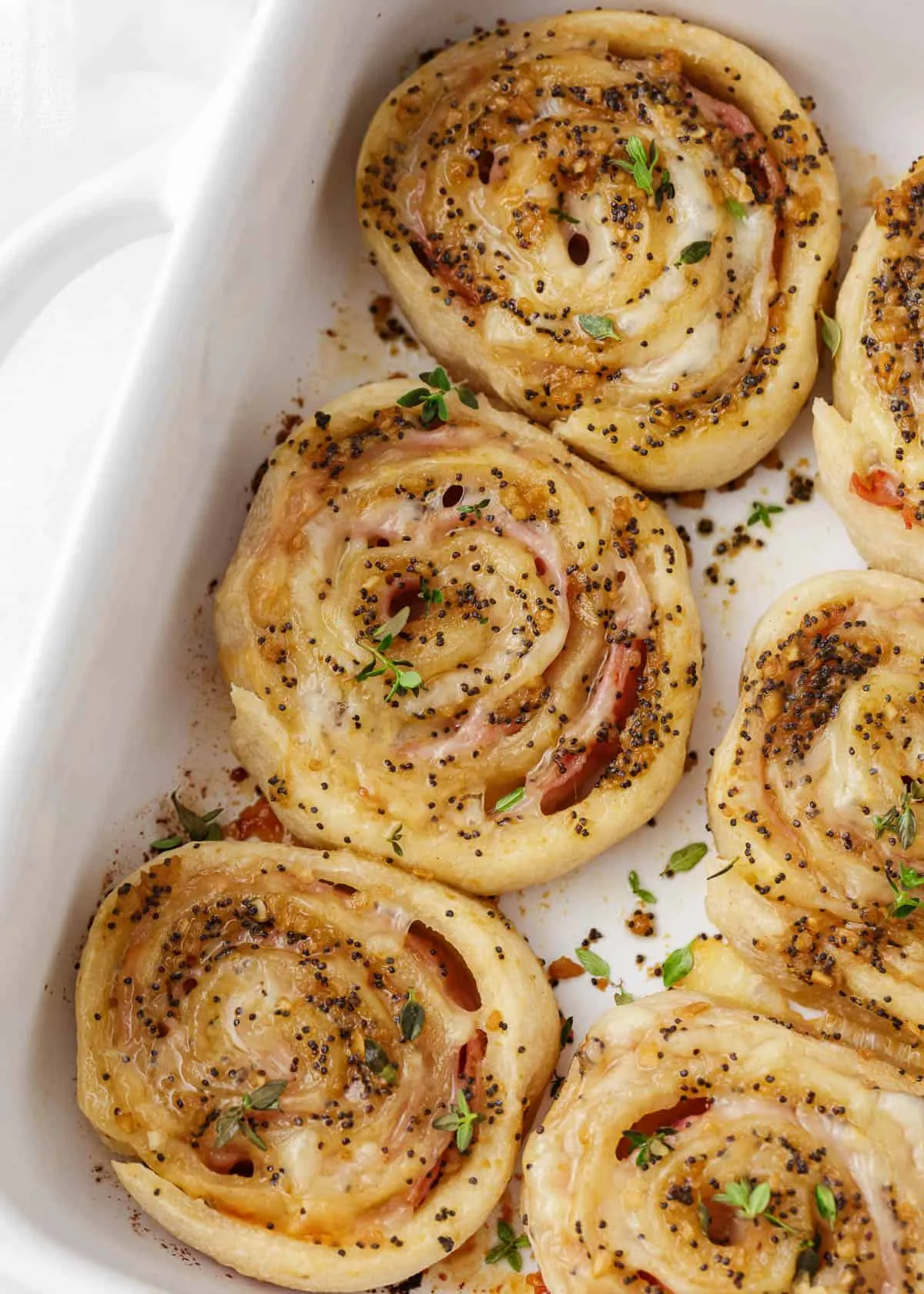 These baked ham and cheese pinwheels are a classic party favorite for a reason. Pizza dough gets rolled up with ham and Swiss cheese, then brushed with a buttery Dijon poppy seed topping before baking until warm and melty. Easy to slice, easy to serve, and always one of the first appetizers to disappear.