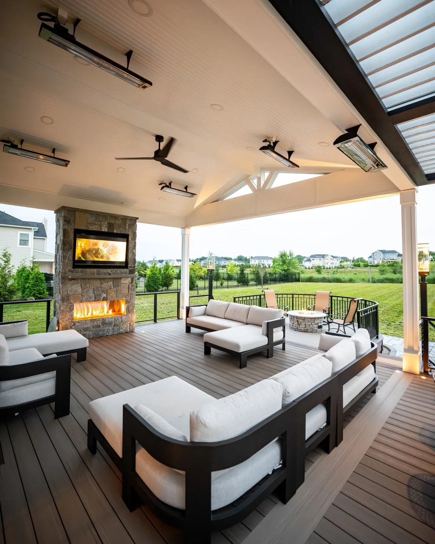 This large covered backyard deck with a fireplace is made for year-round use and serious lounging. The solid roof, ceiling fans, and built-in heaters turn this into a true extension of the house, while the fireplace anchors the space and makes it feel cosy even when the temperature drops. This style is ideal for larger yards where you want a dedicated entertaining zone that works for family nights, hosting friends, and everything in between. It’s a great example of backyard deck ideas screened porches / covered decks that feel polished and comfortable rather than outdoorsy and temporary, and it shows how decking can replace the need for a separate patio altogether.