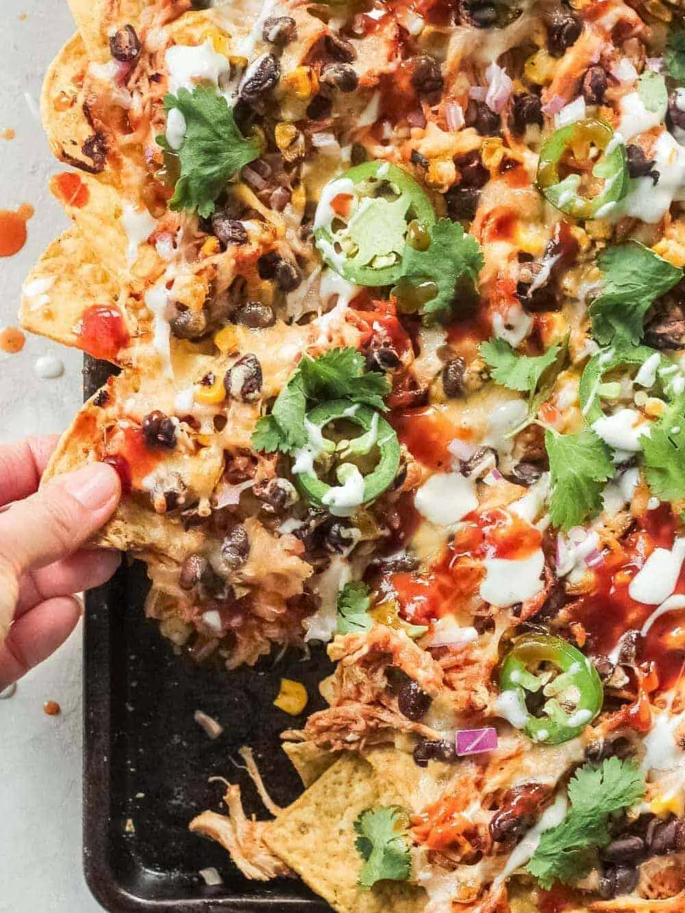These BBQ chicken nachos are the ultimate sheet pan nachos! Made with pulled chicken or rotisserie chicken, they’re one of my fave game day appetizers, and they're ready in just 20 minutes.