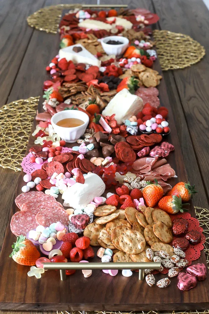 This pink food board is made for a crowd. The long, overflowing layout gives it a big “wow” factor, making it ideal for a Valentine’s party or Galentine’s gathering where people will be grazing all evening. It mixes sweet and savory elements in a way that feels abundant and celebratory rather than formal. This is the kind of board you build when food is part of the décor and you want the table to feel festive, generous, and very much the center of attention.