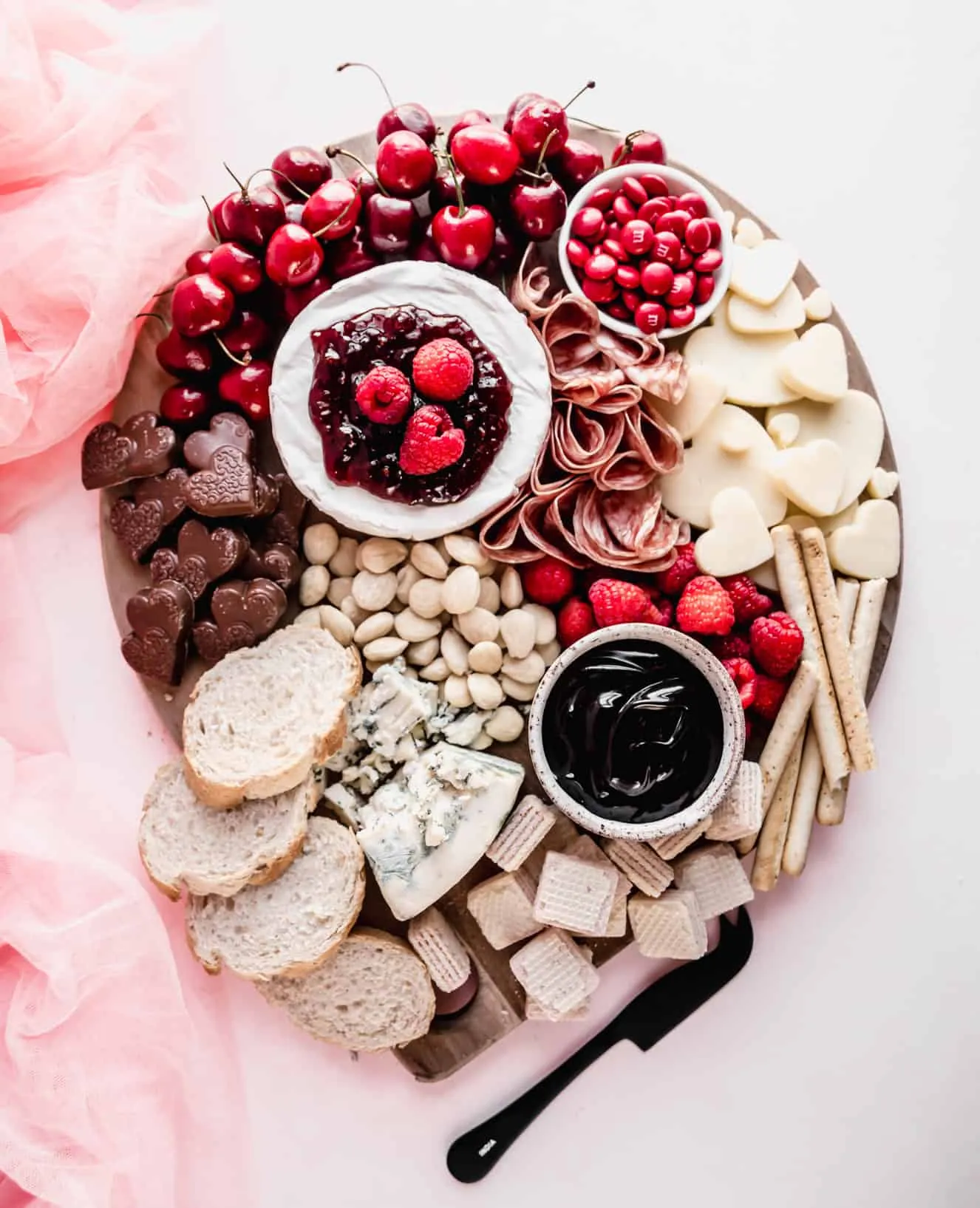 This pink food board leans elegant rather than candy-heavy, mixing soft blush and deep red tones for a more grown-up Valentine’s feel. Fresh fruit, creamy cheeses, and sweet accents are arranged in a relaxed, romantic style that feels perfect for date night, Galentine’s, or a small gathering.