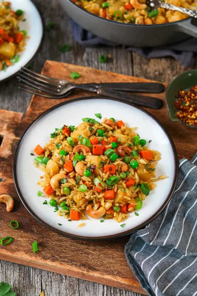 This vegan pineapple fried rice is a sweet, savory, and lightly spicy meal that comes together in about 30 minutes. Frozen peas and roasted cashews make it more filling while adding great texture, and warm curry powder, tamari, and fresh ginger bring plenty of bold flavor. Finished with fresh cilantro, it’s a simple but satisfying pineapple-packed dinner that works perfectly for busy weeknights.
