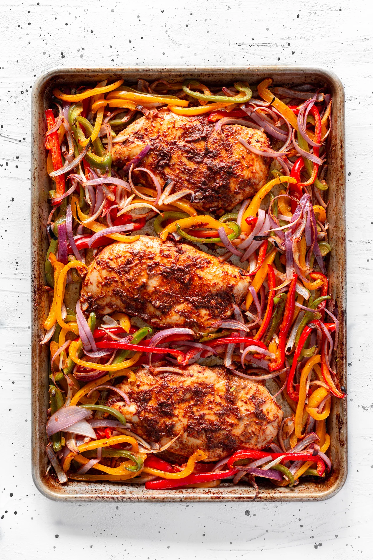 These chipotle sheet pan chicken fajitas bring big, smoky flavor with just the right amount of heat. Chicken, bell peppers, and red onion get tossed in a quick chipotle marinade that comes together in seconds, then everything roasts on one pan until perfectly tender. Ready in about 30 minutes, they’re perfect for serving family-style with all the fixings — avocado, sour cream, and plenty of fresh lime.